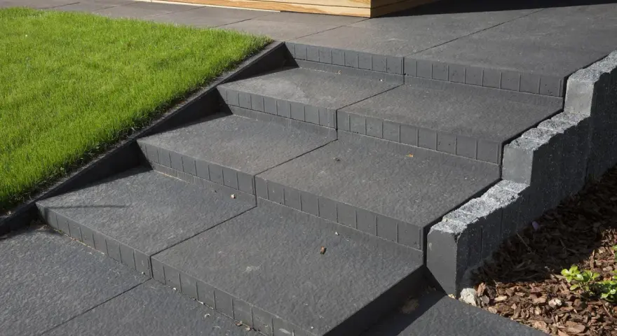 Nowe schody betonowe, proste i nowoczesne, obok trawnika i drewnianej elewacji. Idealne, by pokazać, jak zrobić schody betonowe.