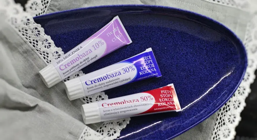 Trzy tubki kremów: Cremobaza 10%, 30% i 50%, ułożone na granatowej tacy.