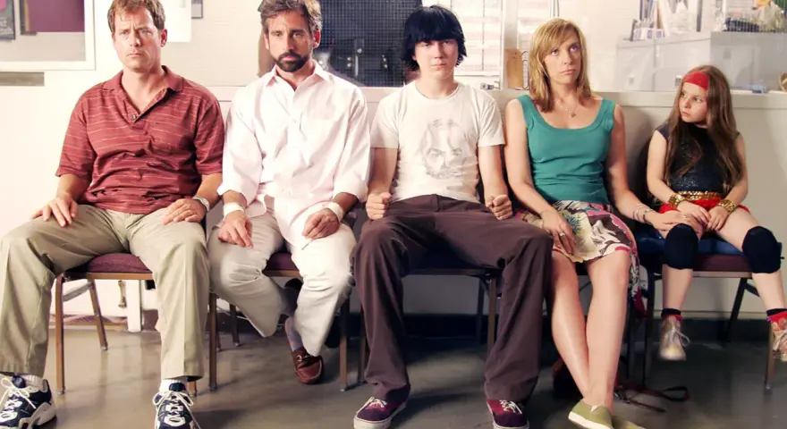 Un gruppo di persone, tra cui Steve Carell, siede in attesa, un momento iconico di film indipendenti famosi.
