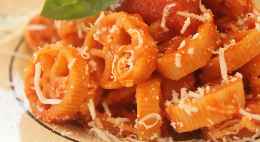 Pasta con ruote e rigatoni conditi con una ricca salsa di pomodoro Bimby, spolverata di parmigiano e guarnita con una foglia di basilico.