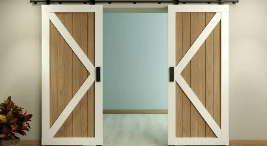 Two white-trimmed, wooden barn doors with black hardware slide open on a black track, showcasing a room beyond. This image illustrates how to install barn door hardware.