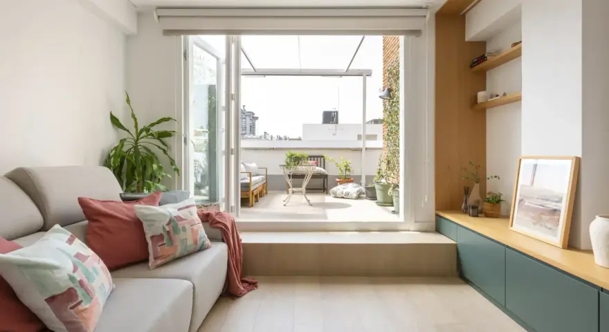 Ideas para decorar un salón rectangular: sofá gris, cojines coloridos, plantas y acceso a terraza.