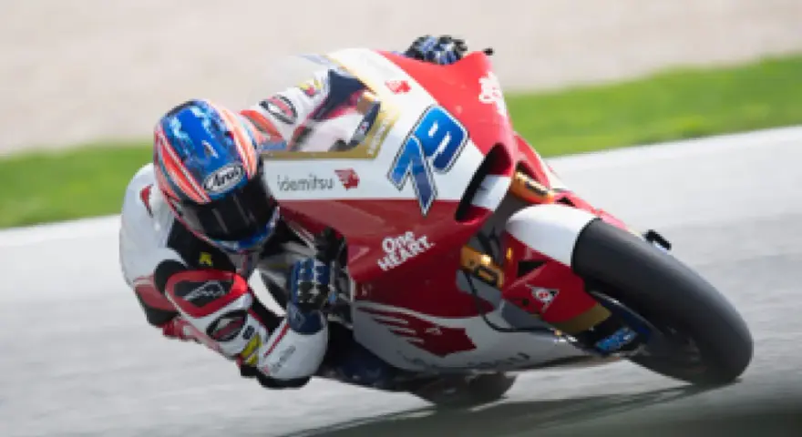 Piloto en plena curva durante una carrera de moto gp. La moto roja y blanca lleva el número 79.