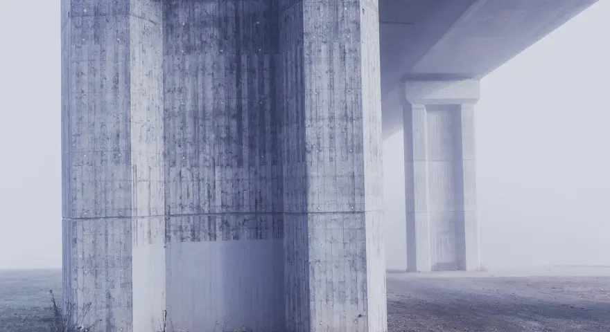 Betonowe filary mostu w gęstej mgle. Różne klasy ekspozycji betonu tworzą ciekawe tekstury.