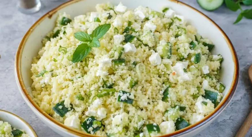 Frischer Couscous-Salat mit Gurkenwürfeln, Feta und Minze, garniert mit einer Minz-Dolde.