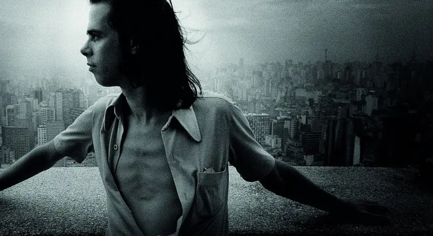 Młody Nick Cave, z rozwianymi włosami, spogląda na miasto. Jego muzyka, jak ten widok, pełna jest mroku i piękna.