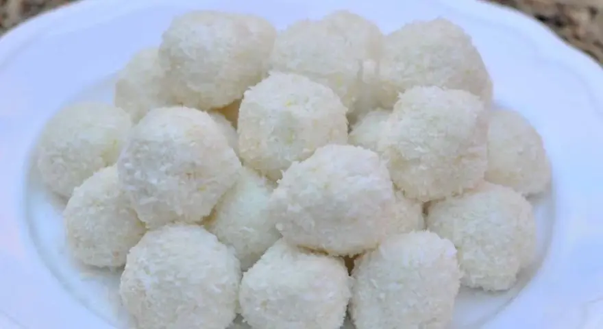 Un mucchio di dolci palline di cocco su un piatto bianco, perfette per una pausa golosa.
