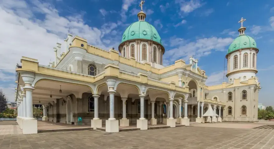 Katedra Świętej Trójcy w Addis Abebie, z zielonymi kopułami i kolumnowym portykiem, pod błękitnym niebem.
