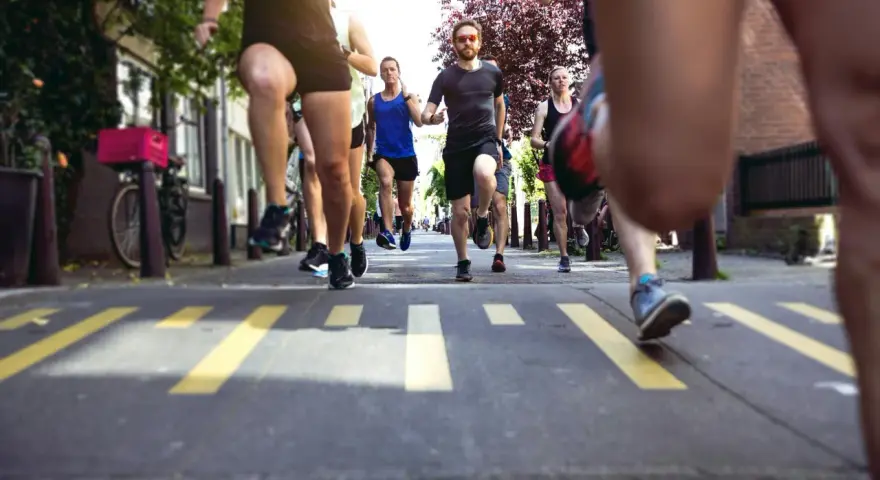 En grupp löpare kämpar sig fram på asfalten, redo att springa halvmaraton. Gula linjer på vägen markerar banan.