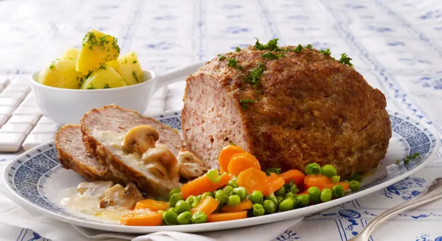 Herzhaftes Hackbraten-Mittagessen nach Omas Rezepten, serviert mit Salzkartoffeln, Pilzrahmsoße und Gemüse.