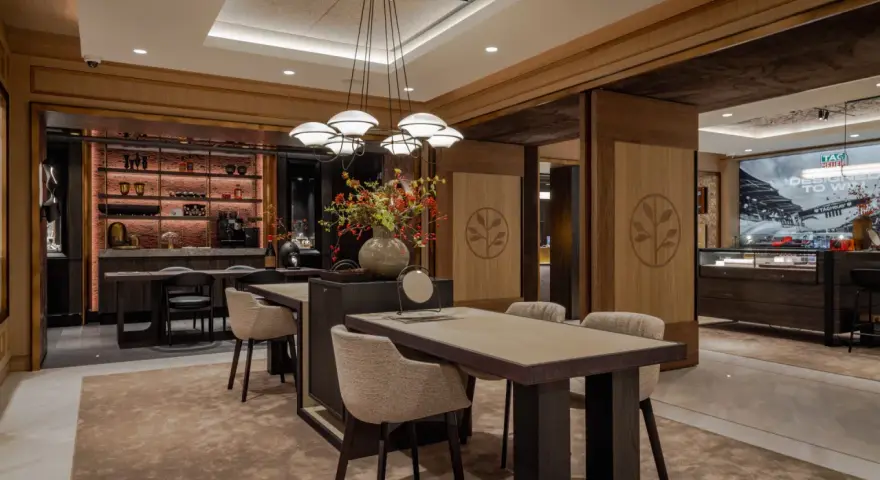 Interno di un elegante **progetto gioielleria** con tavoli in legno, sedie imbottite, un'area bar e vetrine espositive.