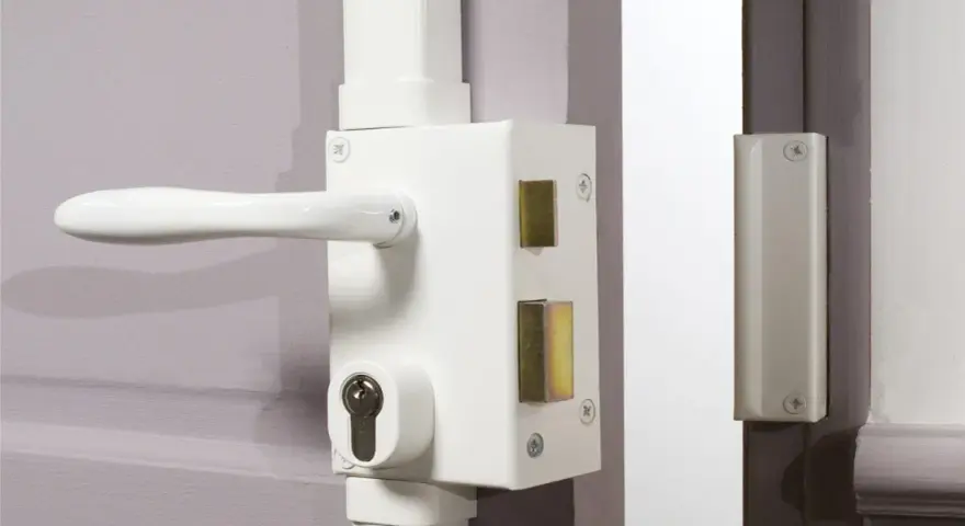 Poignée et serrure blanche avec barillet visible, prête à être verrouillée. Une clé de chaque côté assure la sécurité.