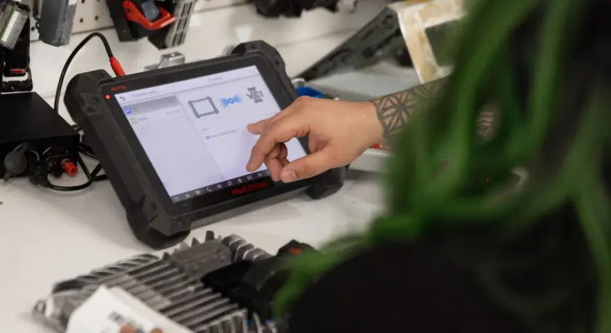 Mechanic uses a diagnostic tablet to connect to a car's ecm.
