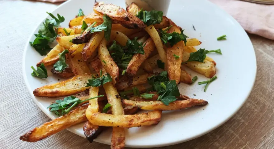 Chrupiące frytki z air fryera, posypane natką pietruszki. Idealne na szybki obiad, proste air fryer przepisy obiad.