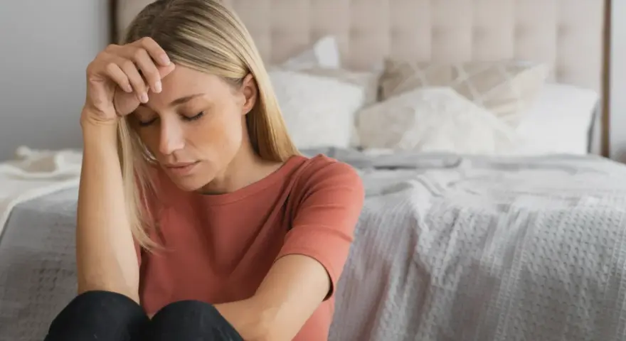 Kvinna med slutna ögon, handen mot pannan. Kanske en känsla av depression under klimakteriet, men det finns behandling.