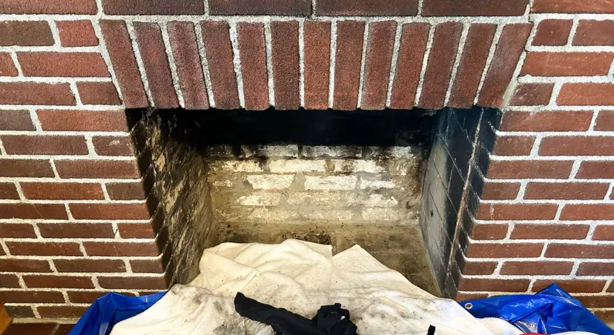 Camino in mattoni pronto per la pulizia. Il braciere è vuoto, ma c'è un allarme per la stufa a pellet.