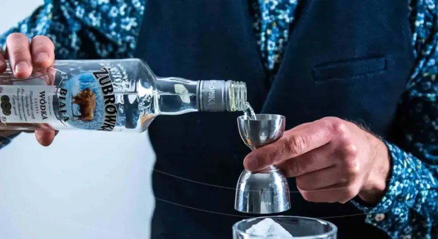 Barman nalewa Żubrówkę do kieliszka z lodem. To może być początek przygotowania drinka z jednej z top 10 wódek w Polsce.