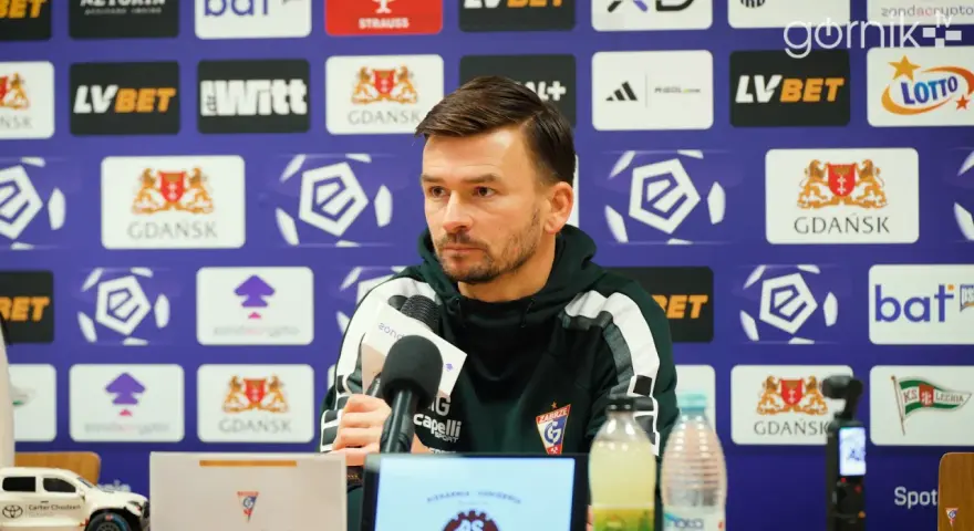 Trener rozmawia o lechia transfery. Na ścianie logo Lechii Gdańsk.