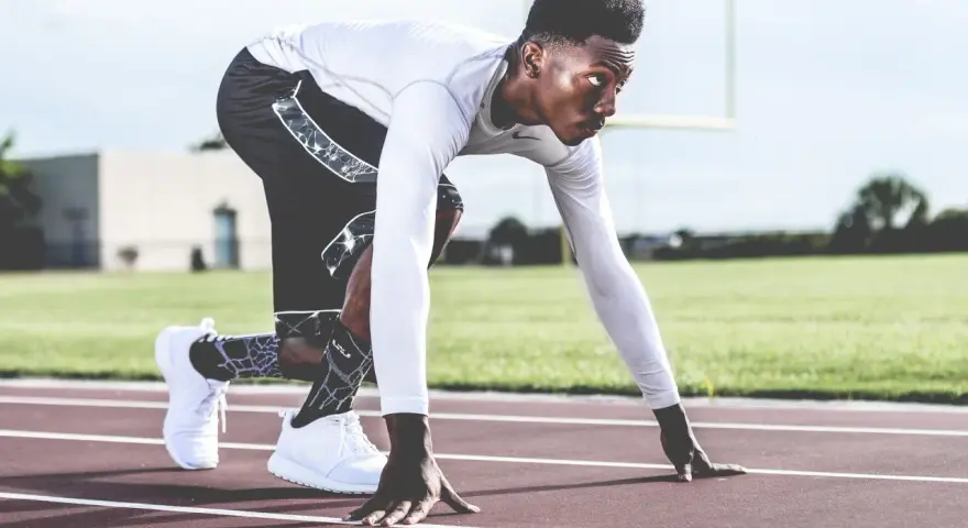 En sprinter i startblocken, redo för en explosiv anaerob sprint. Träningen balanserar aerob och anaerob kondition.