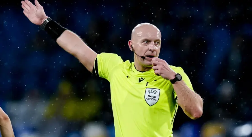 Sędzia piłkarski w żółtej koszulce z naszywką UEFA, dmucha w gwizdek. Zastanawiasz się, ile zarabia sędzia piłkarski?