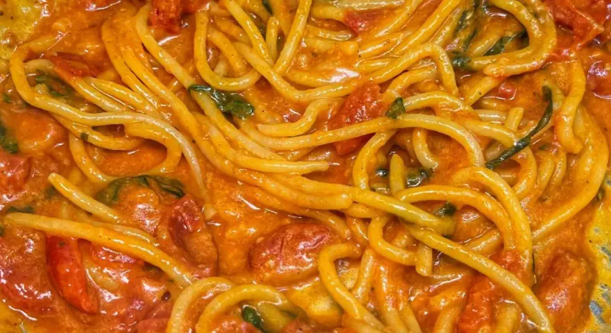 Spaghetti avvolti in un sugo cremoso di pomodoro e basilico, un invitante piatto di pasta allo scarpariello.
