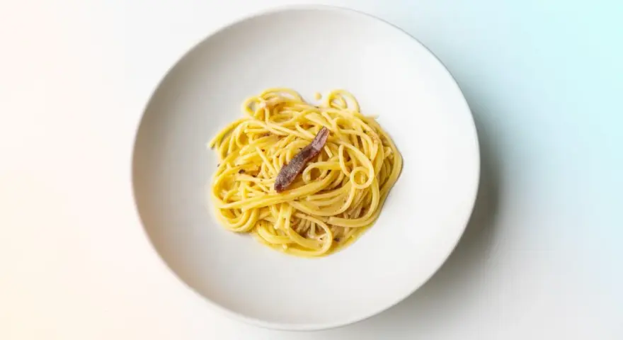 Spaghetti mit einer Sardelle, die zeigt, was sind Sardellen: kleine, salzige Fische, die Pasta verfeinern.