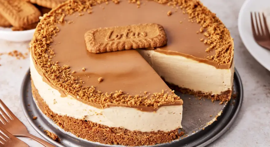 Ein cremiger Lotus Cheesecake mit Karamellglasur und Keksbröseln, dekoriert mit einem Lotus-Keks.