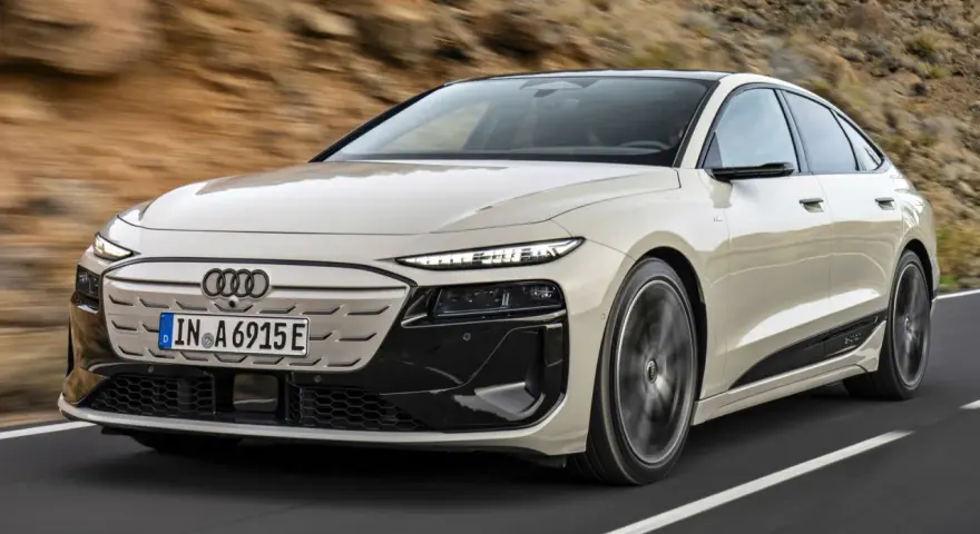 Jasnoszary Audi A6 e-tron z czarnymi akcentami jedzie po drodze.
