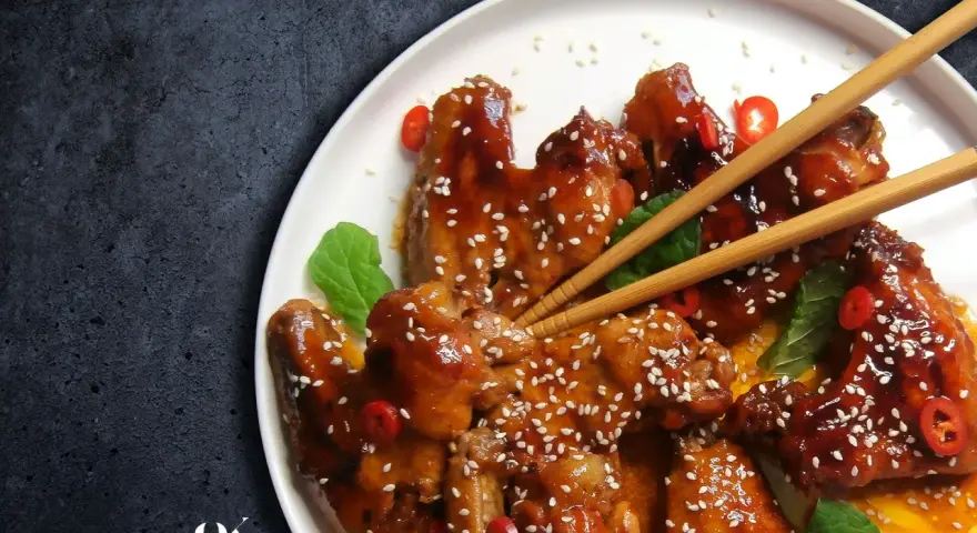 Pyszne skrzydełka teriyaki, błyszczące od sosu, posypane sezamem i ozdobione plasterkami chili.