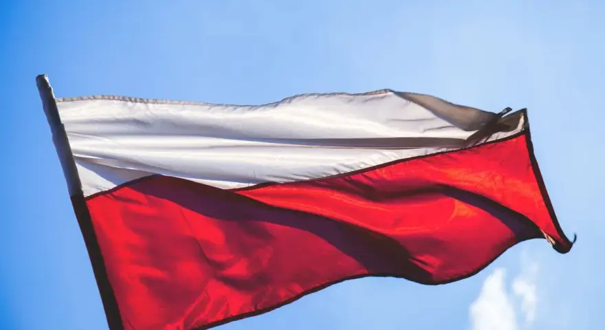 Flaga Polski, biało-czerwona, powiewa na tle błękitnego nieba.