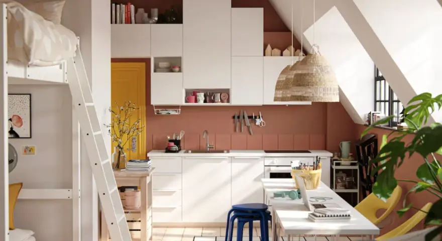 Aménager un studio : lit mezzanine, cuisine blanche, porte jaune, et coin bureau fonctionnel sous les combles.
