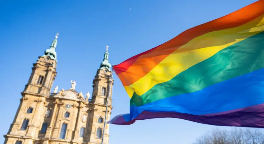 Regenbogenfahne weht vor evangelischer Kirche. Ein Zeichen für Akzeptanz und Vielfalt, das die Botschaft der evangelischen Kirche LGBT widerspiegelt.