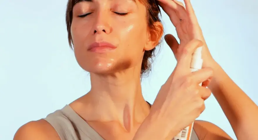 Mujer se aplica bruma facial para refrescar e hidratar su piel. Descubre para que sirve la bruma facial y luce un rostro radiante.