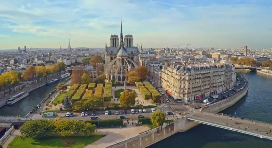 Vista aérea de la Île de la Cité en París, con la majestuosa Catedral de Notre Dame en el centro, rodeada de edificios históricos y el río Sena.