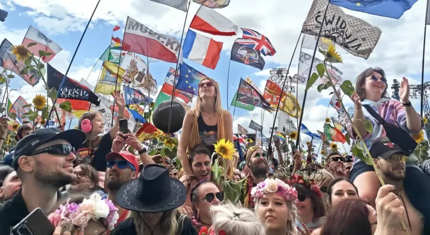 Tłum na festiwalu Poland Rock 2026, z flagami i słonecznikami. Ludzie cieszą się muzyką i atmosferą.