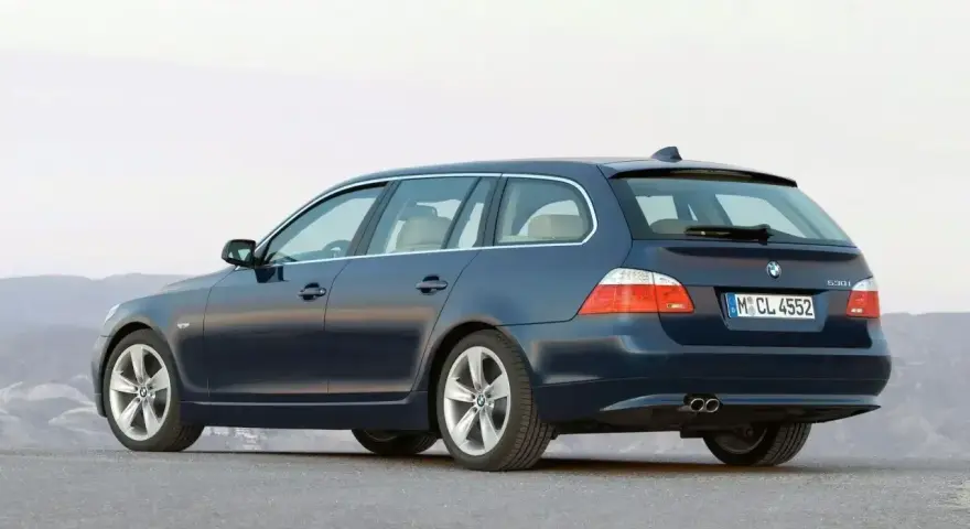 Granatowe BMW E61, kombi, stoi na pustej drodze.