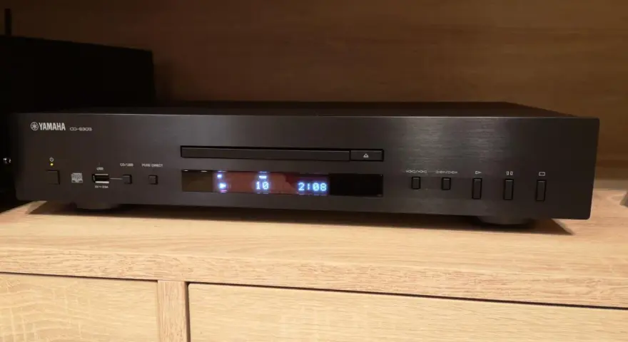 Czarny odtwarzacz CD Yamaha CD-S303 na drewnianej półce, gotowy do testu. Wyświetlacz pokazuje utwór 10 z 2:08.