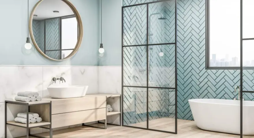 Salle de bain moderne avec baignoire îlot, douche vitrée et lavabo sur meuble en bois. Le mur derrière la douche est recouvert de **faïence** bleu sarcelle en chevrons.