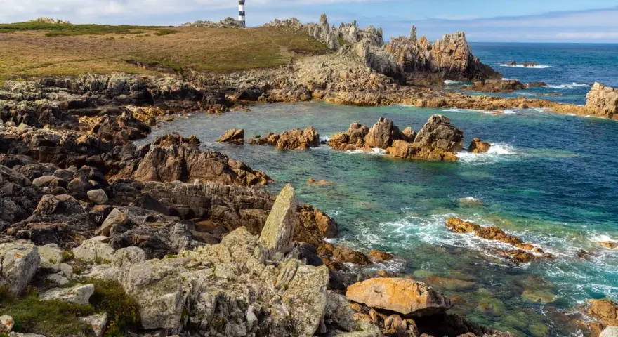 Phare noir et blanc sur une côte rocheuse et sauvage d'Ouessant. Combien de temps pour visiter Ouessant ? Une journée suffit pour admirer ce paysage.