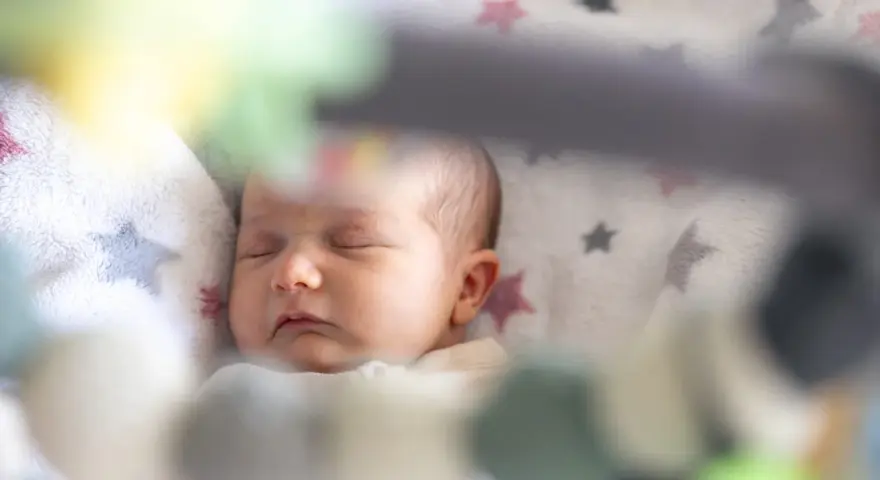 Śpiące dziecko na kocyku w gwiazdki. Może to być moment regresu snu, kiedy maluch potrzebuje więcej spokoju.