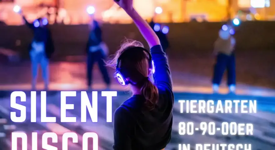 Silent Disco Berlin im Tiergarten. Leute tanzen mit leuchtenden Kopfhörern im Dunkeln.