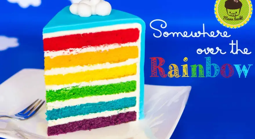 Ein Stück regenbogen kuchen mit bunten Schichten und Wolken-Deko.