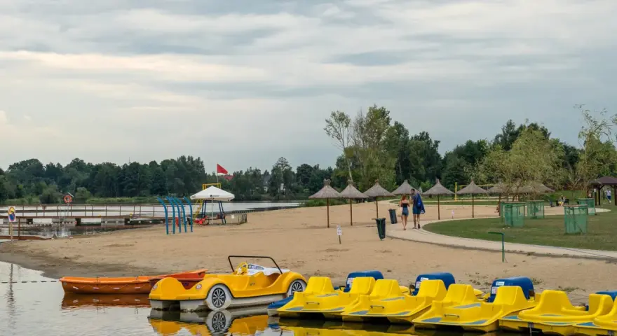 Żółte rowerki wodne i łódki czekają na plaży. Idealne miejsce na wypoczynek, jak na Mazurach blisko Warszawy.