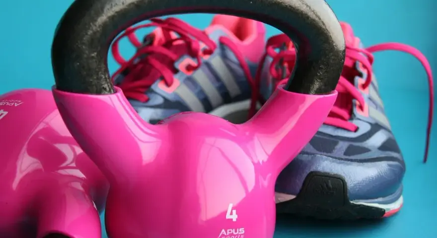 Różowe kettlebelle i buty sportowe marki Adidas gotowe do treningu.