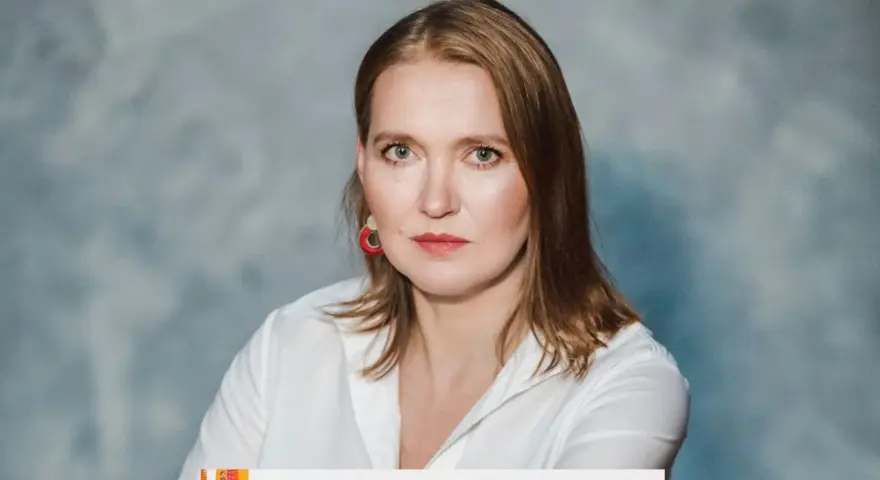 Kobieta w białej koszuli, z rudymi włosami i czerwoną biżuterią, udziela wywiadu. #16 Jak, krok po kroku, zrobić wywiad?
