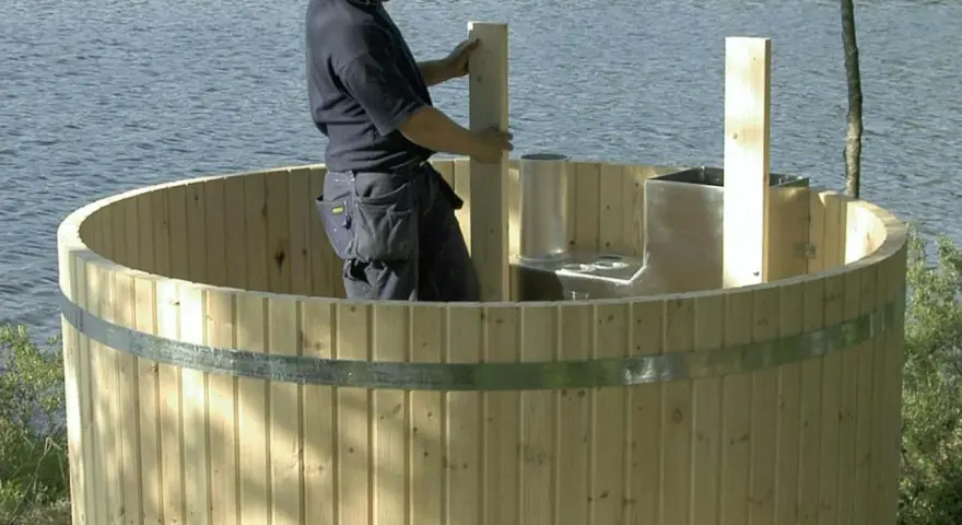 Man bygga badtunna vid sjön. Träet är nytt och redo för montering.