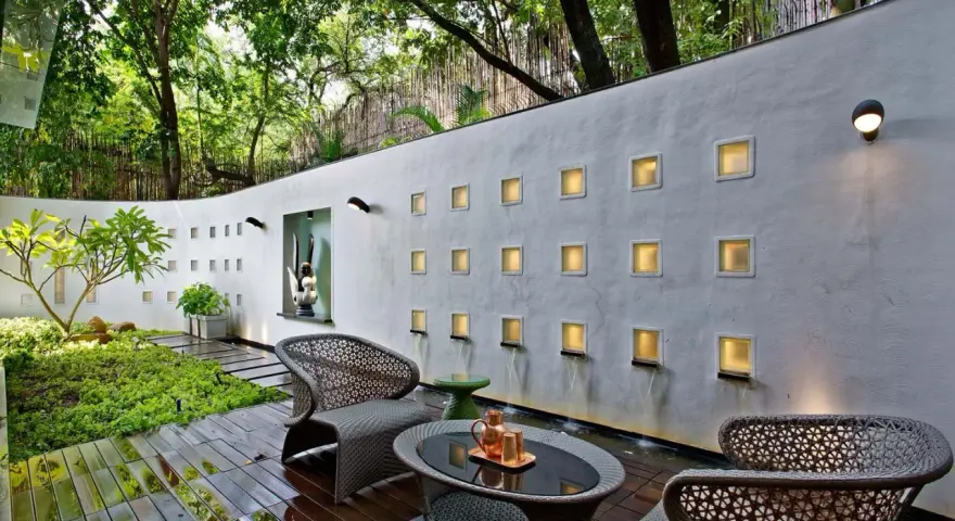 Un oasis moderno para decorar pared terraza pequeña. Muebles de mimbre, plantas exuberantes y cascadas de agua crean un ambiente sereno.