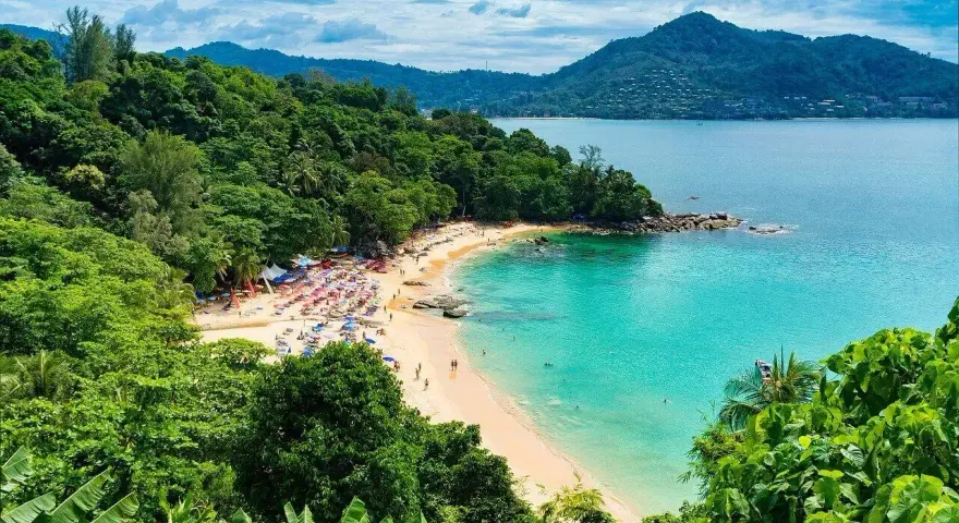 Tropikalna plaża z turkusową wodą, zielonymi wzgórzami i leżakami.