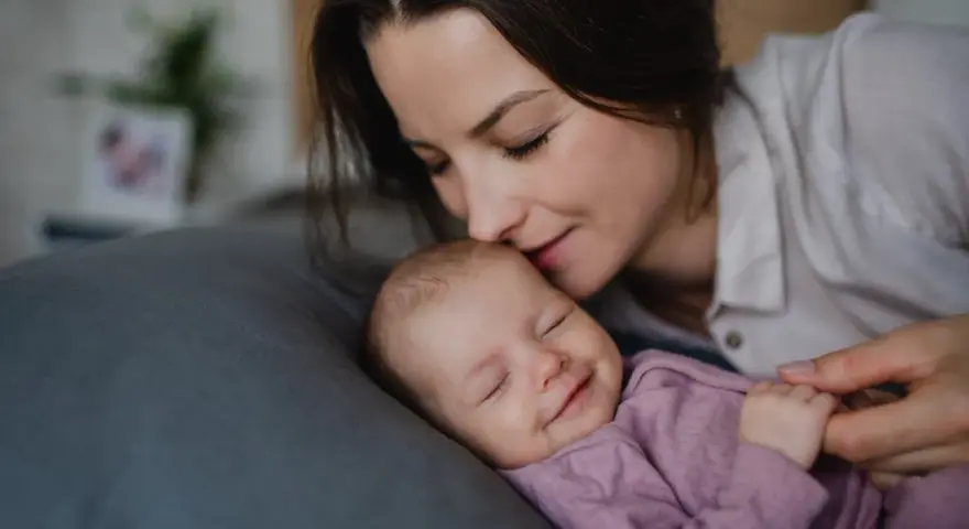 Mama całuje śpiące dziecko. Wkrótce wybierzemy dla niej słodkie imiona dla dziewczynki.