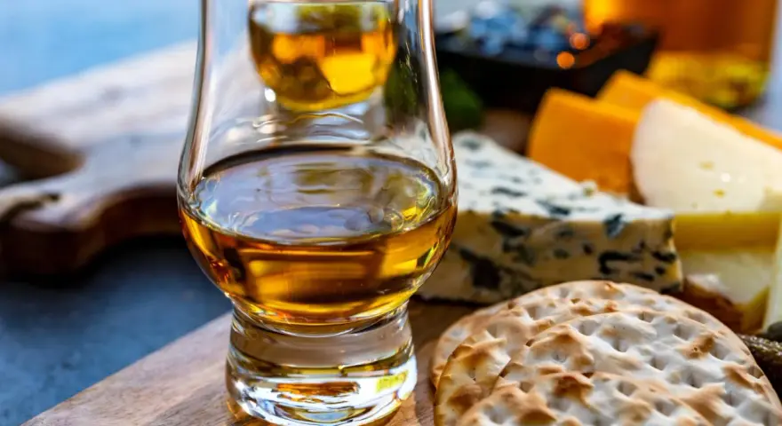 Szklanka whisky i sery na desce. Idealne na degustacje whisky online.